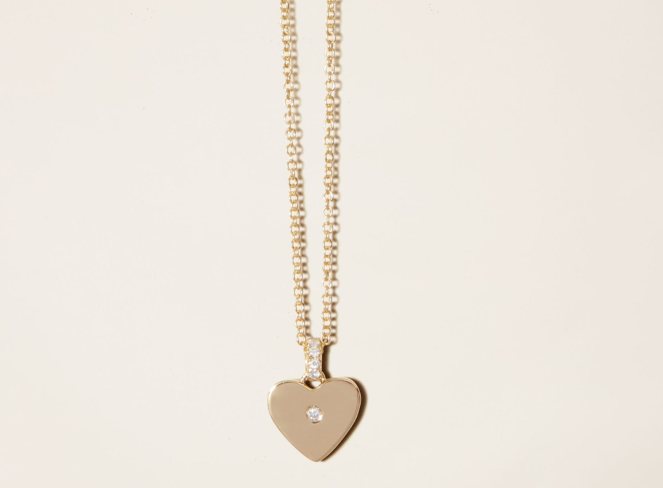 a gold necklace with a heart-shaped pendant and a diamond