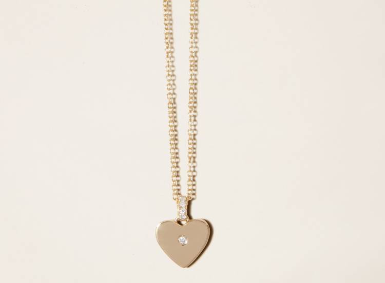 a gold necklace with a heart-shaped pendant and a diamond