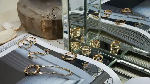 a bunch of gold jewelry is sitting on top of a magazine in front of a mirror