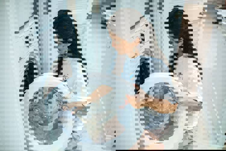 a woman is kneeling down in front of a washing machine