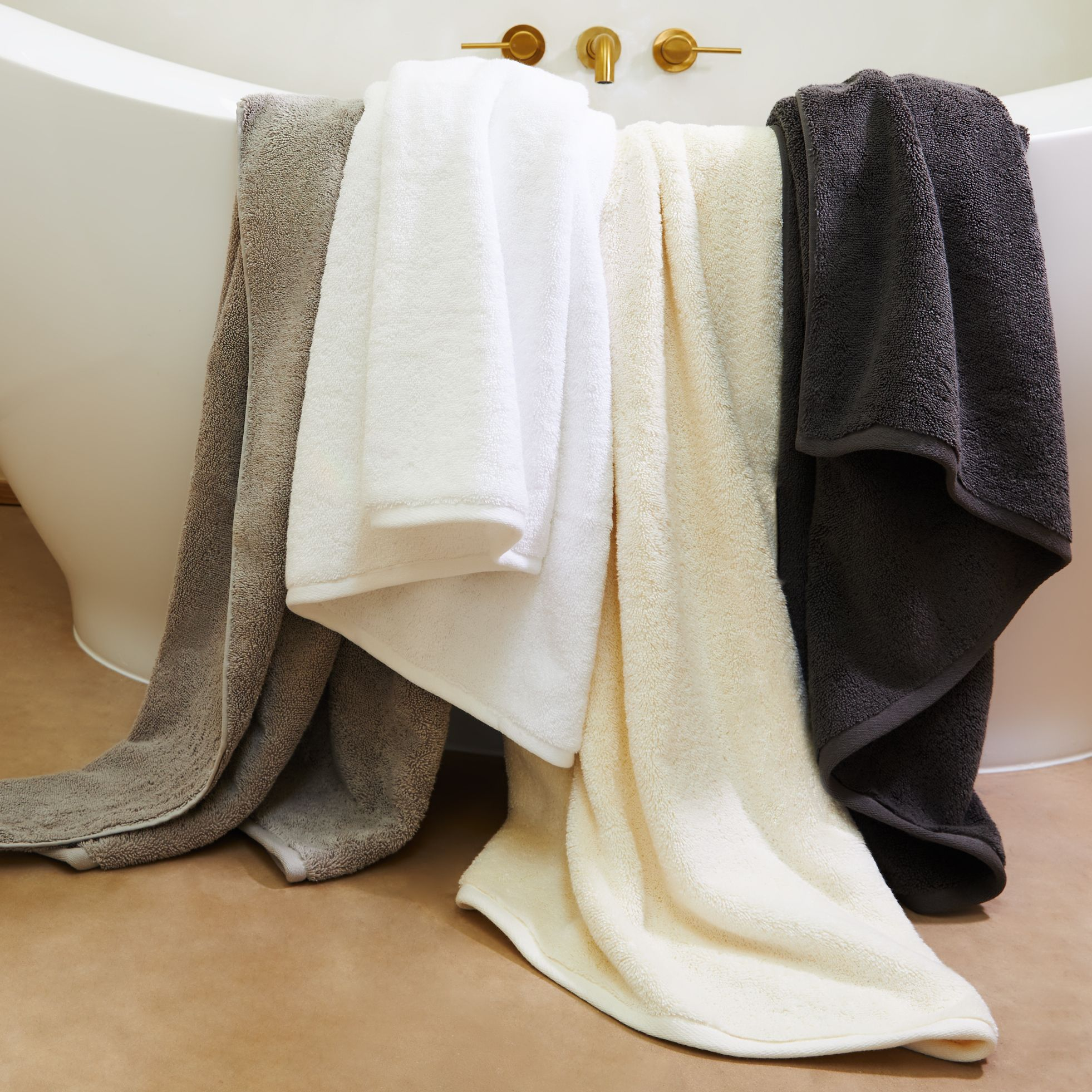 a bunch of towels are stacked on top of each other next to a bathtub