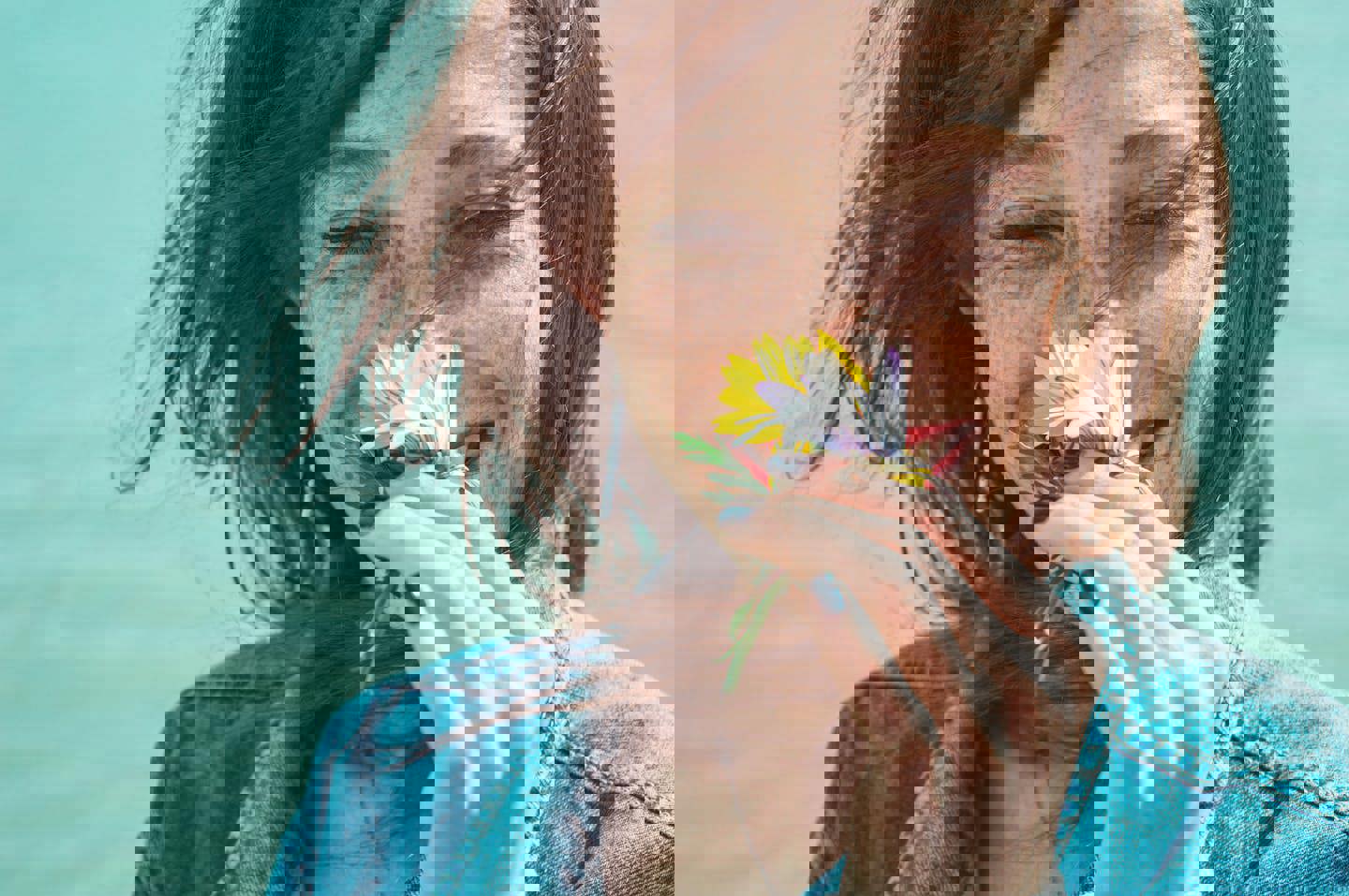 a woman with freckles is holding a flower in front of her face