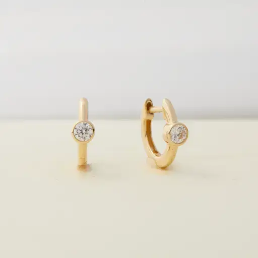 a pair of gold hoop earrings with diamonds on a table