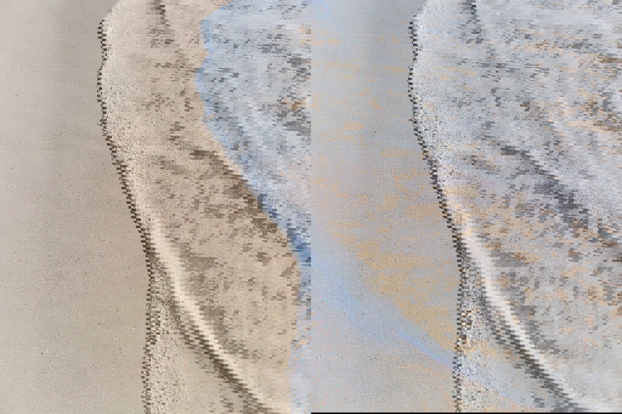 a wave is breaking on a sandy beach