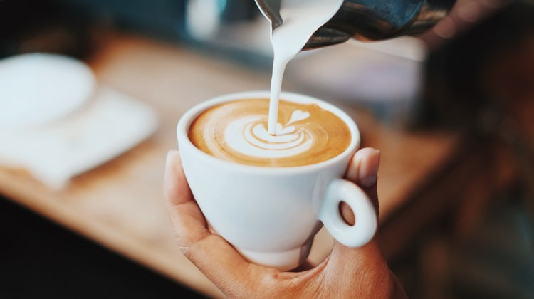 a person is pouring milk into a cup of coffee