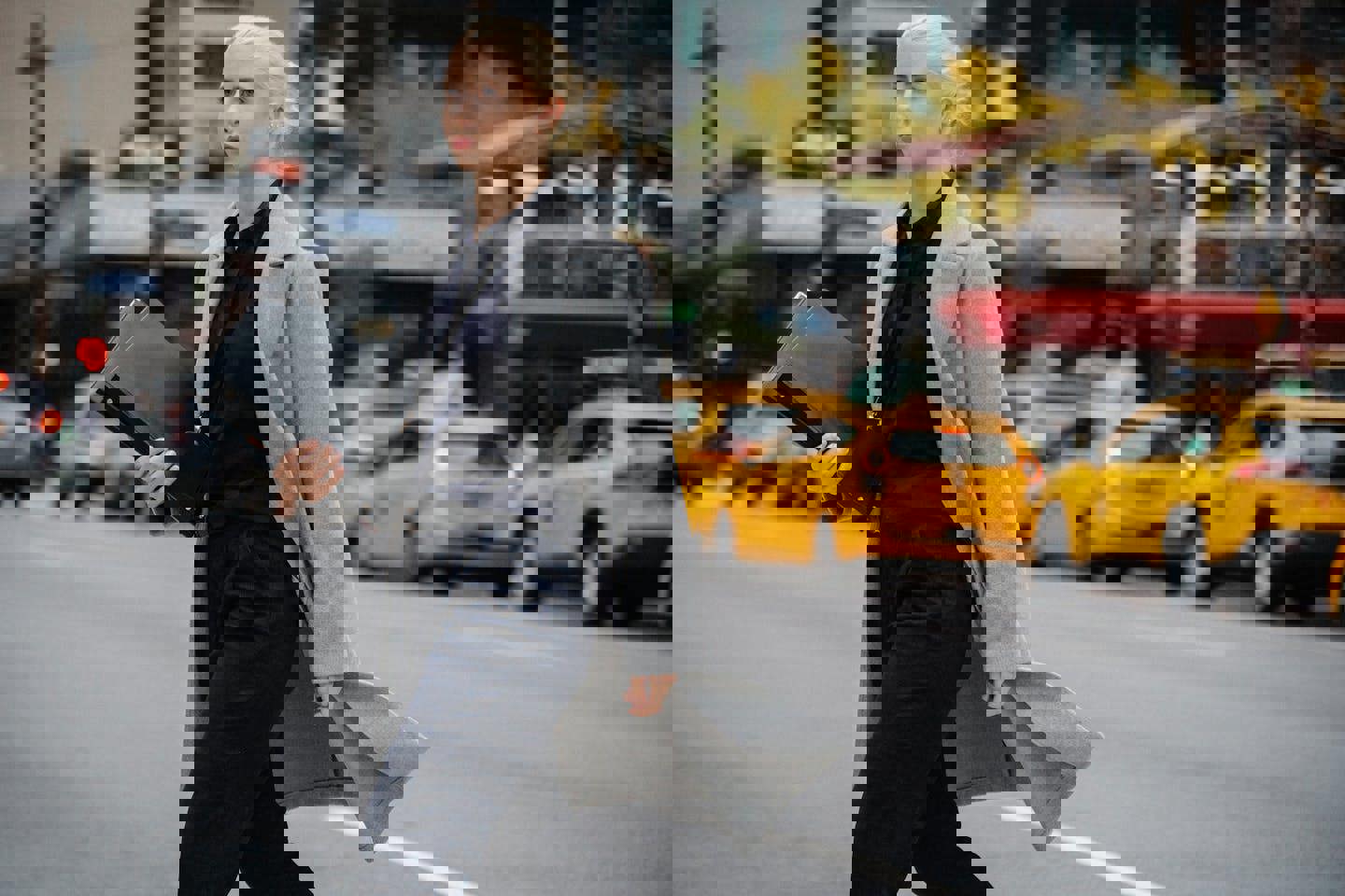 a woman in a grey coat is walking down the street