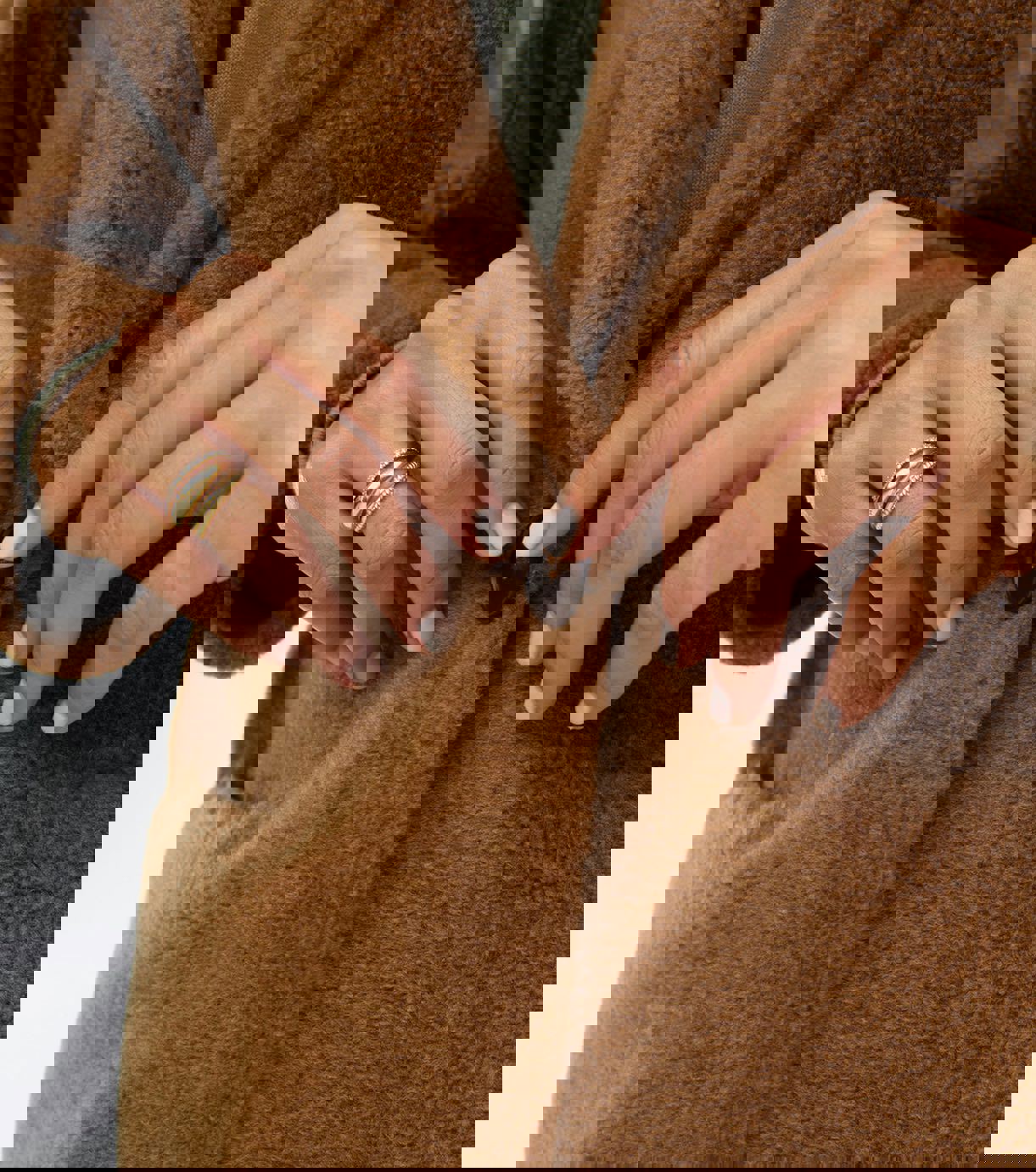 a close up of a person 's fingers on a brown coat