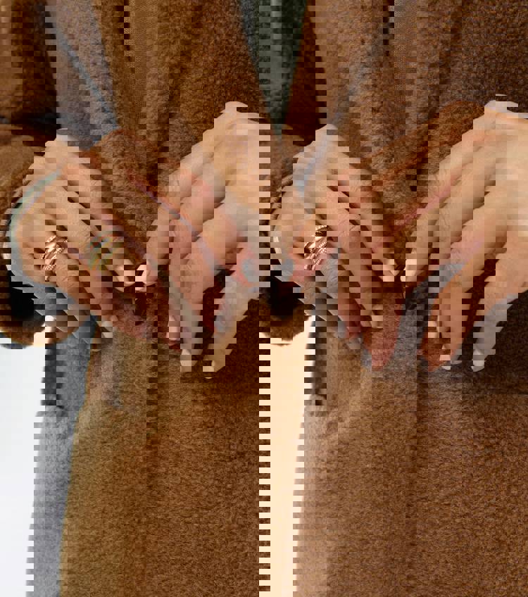 a close up of a person 's fingers on a brown coat