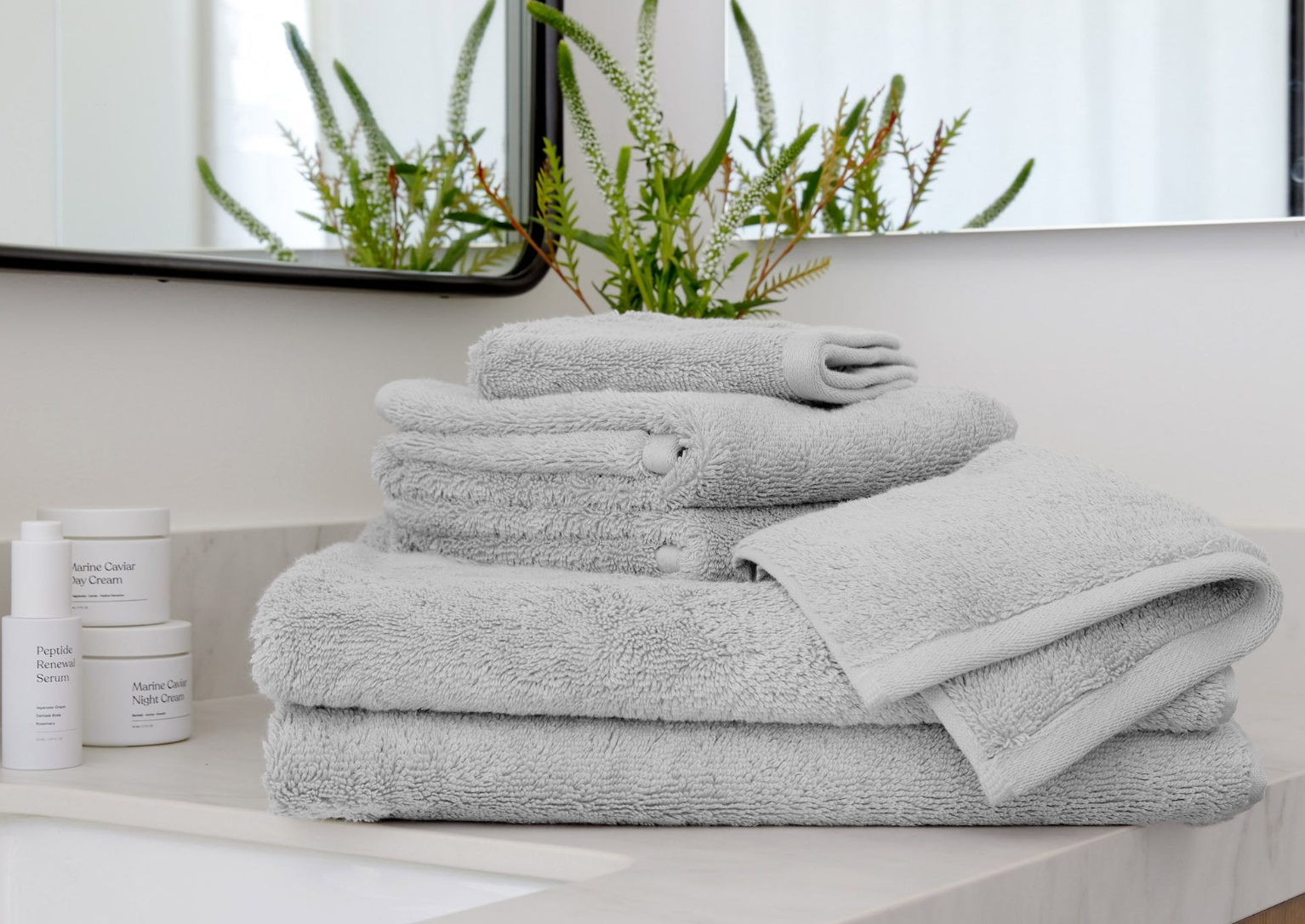 a stack of grey towels sits on a bathroom counter