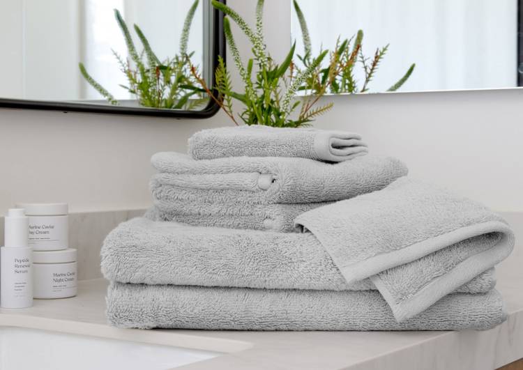 a stack of grey towels sits on a bathroom counter