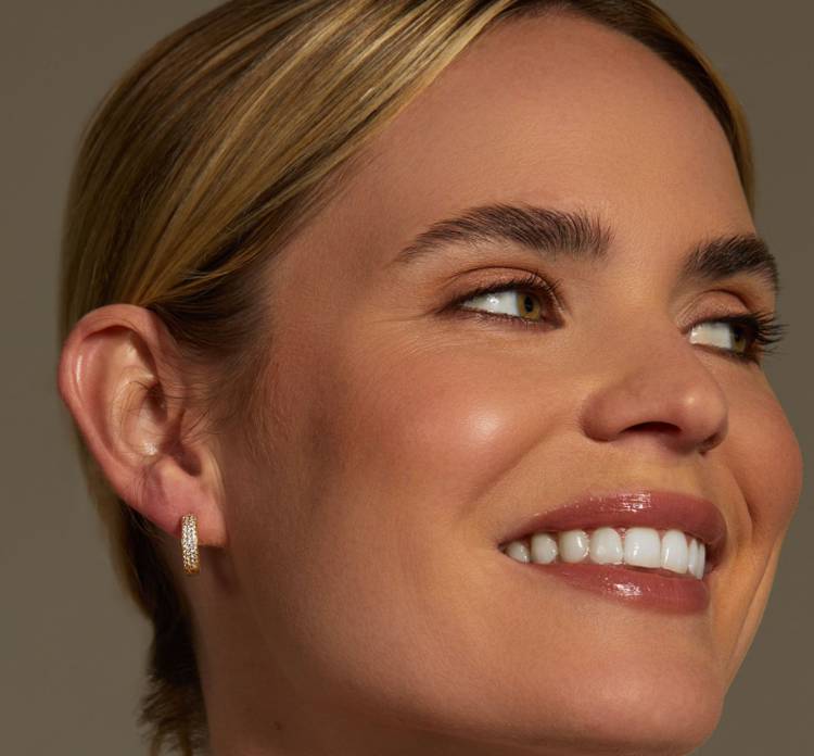 a close up of a woman wearing hoop earrings and smiling