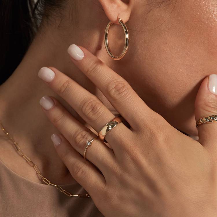 a close up of a woman 's hand wearing rings and earrings