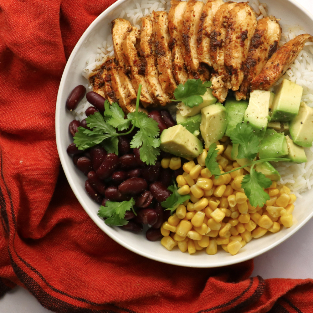 a white bowl filled with rice beans corn and avocado