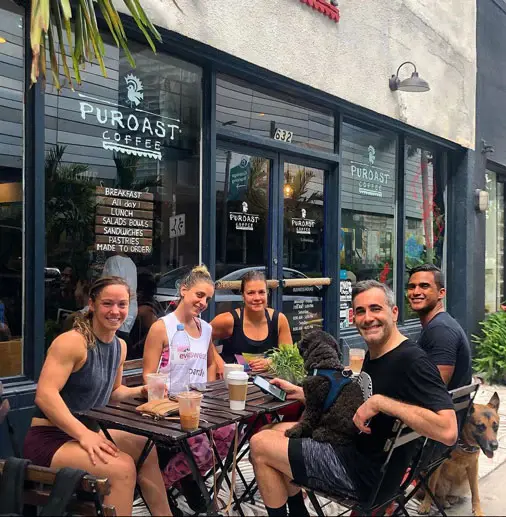 a group of people are sitting at a table outside of a coffee shop