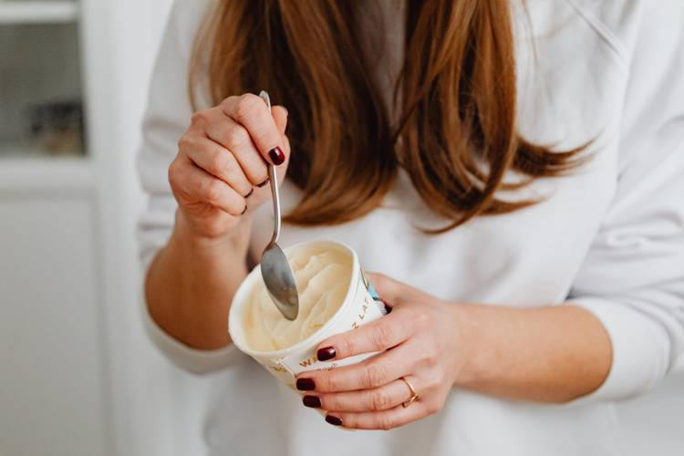 a woman is eating ice cream from a cup with a spoon