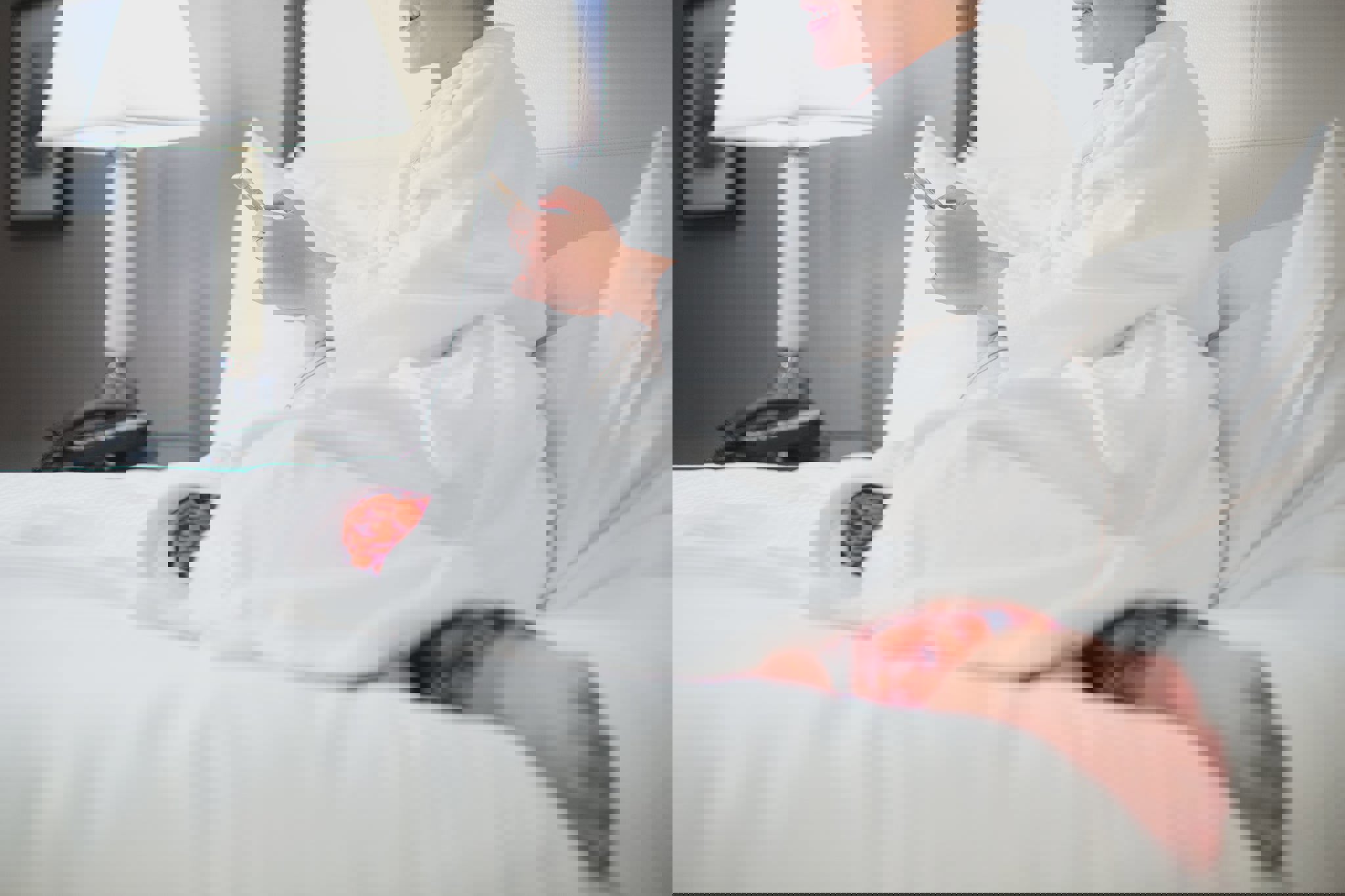 a woman in a bathrobe sits on a bed looking at her phone