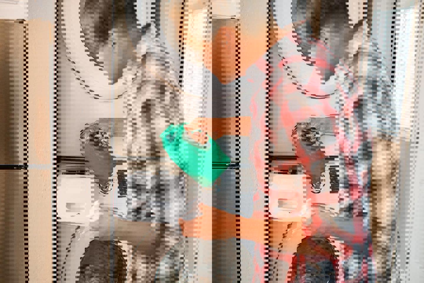 a man is pouring laundry detergent into a stacked washer and dryer