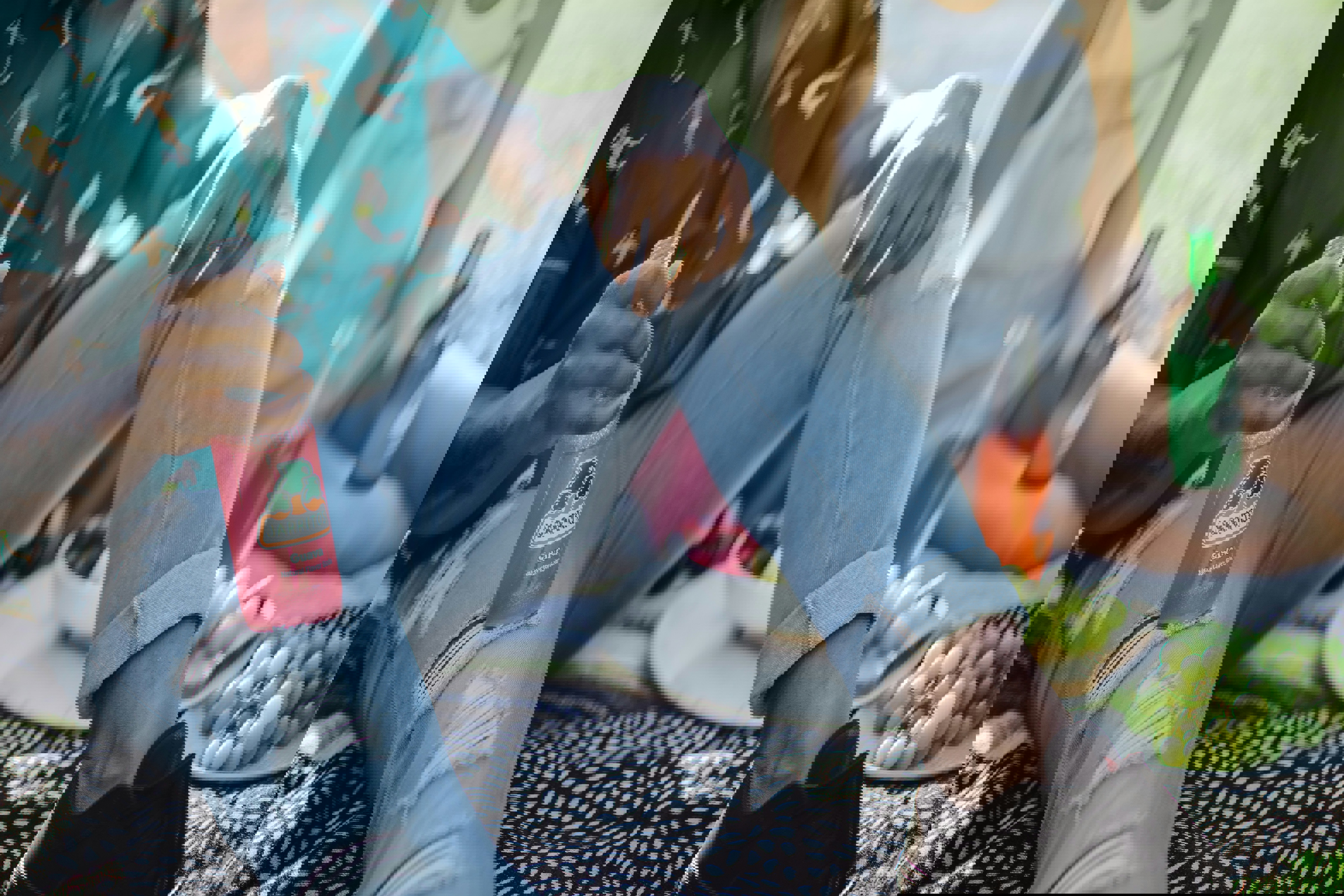 a man sits on a blanket holding a bottle of jarritos