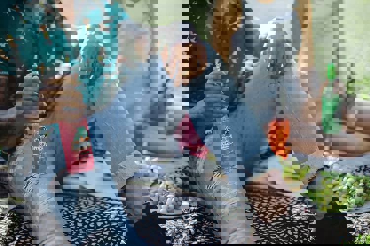 a man sits on a blanket holding a bottle of jarritos