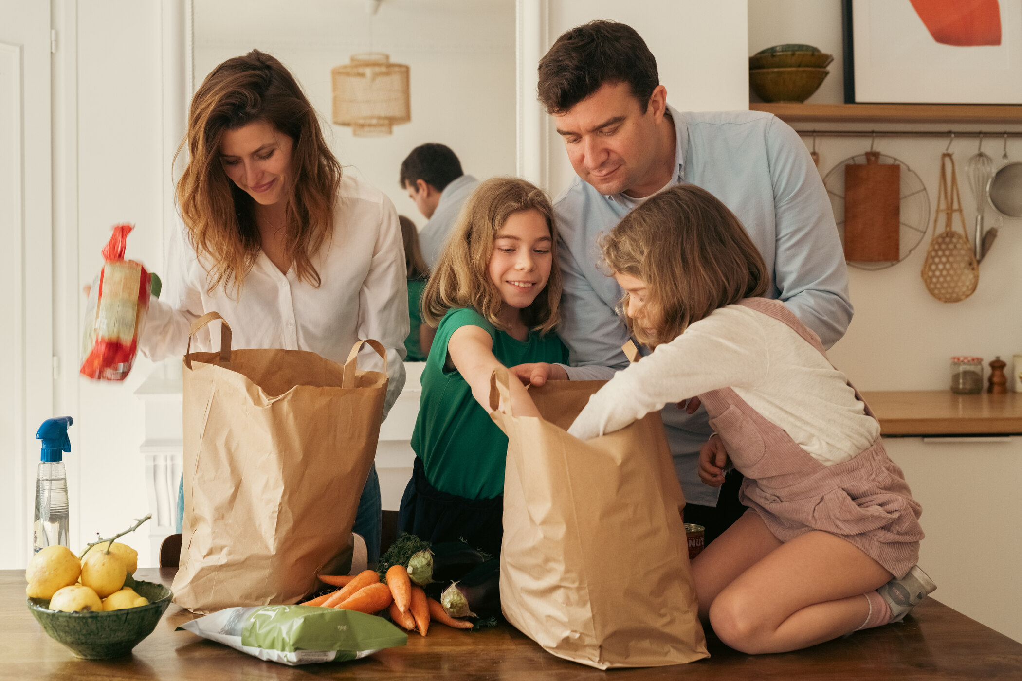 a family gathered around a table with bags of groceries a family gathered around a table with bags of groceries
