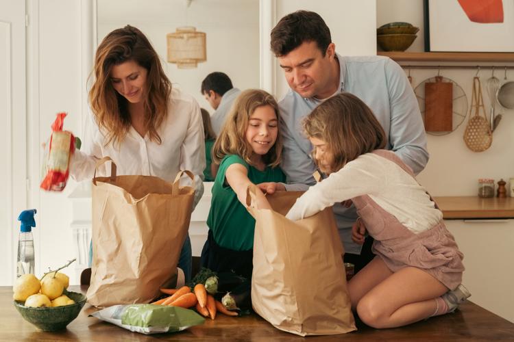a family gathered around a table with bags of groceries