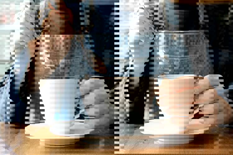 a person is stirring a cup of coffee with a spoon