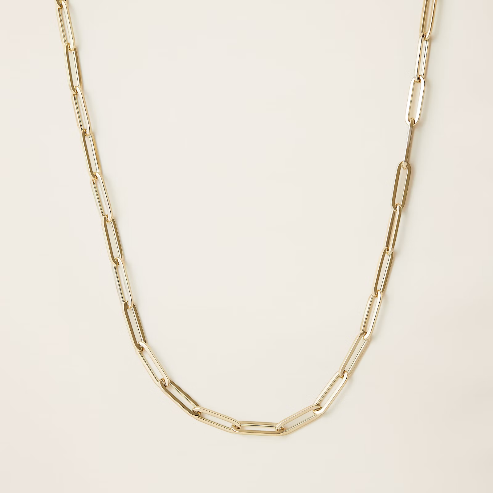 a close up of a gold chain necklace on a white surface