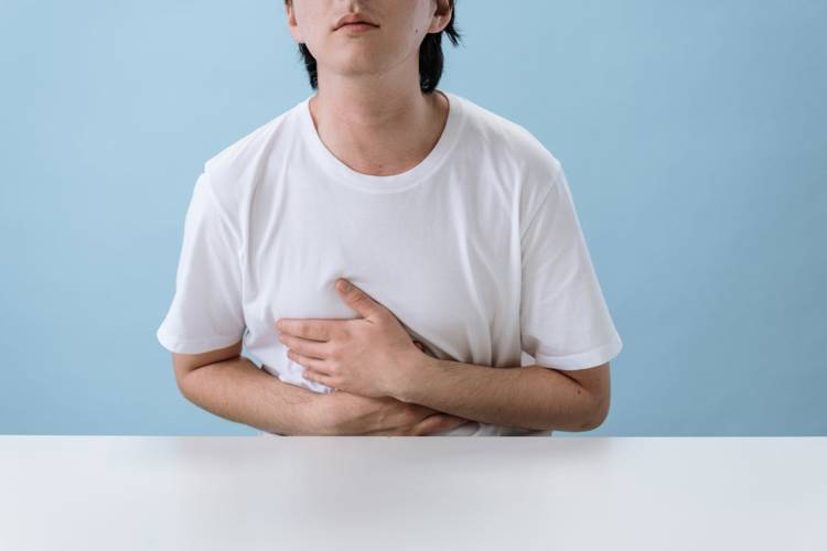 a man in a white shirt is holding his stomach in pain