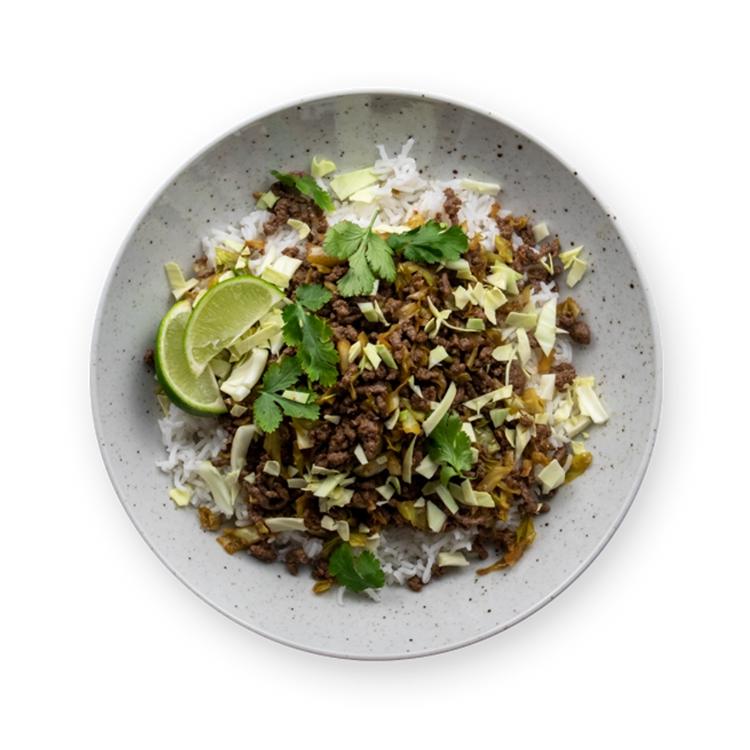 a bowl of food with rice , meat , cabbage and lime wedges on a white background