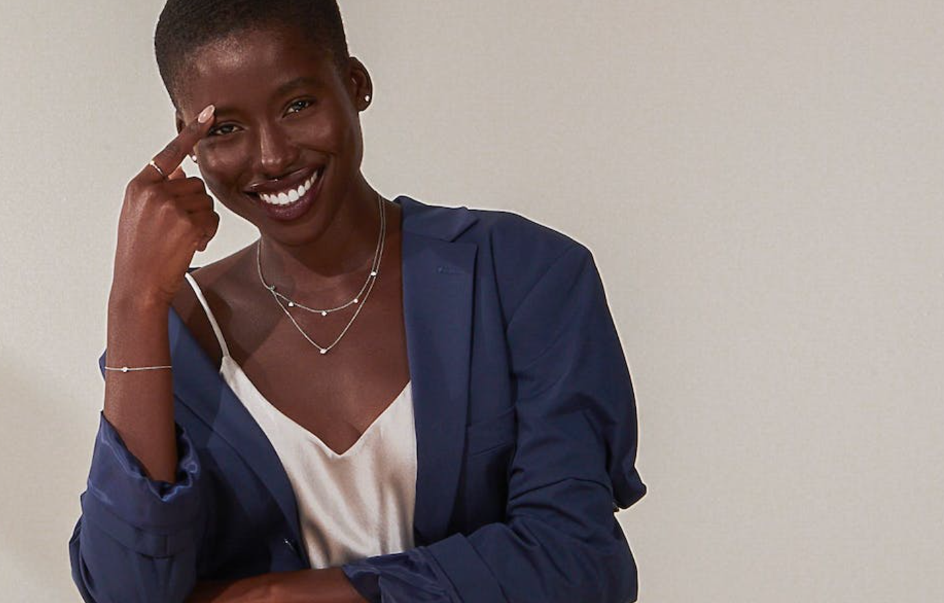 a woman wearing a blue jacket and a white tank top is smiling