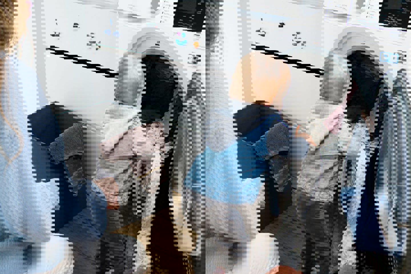 a woman and a baby are doing laundry in a washing machine