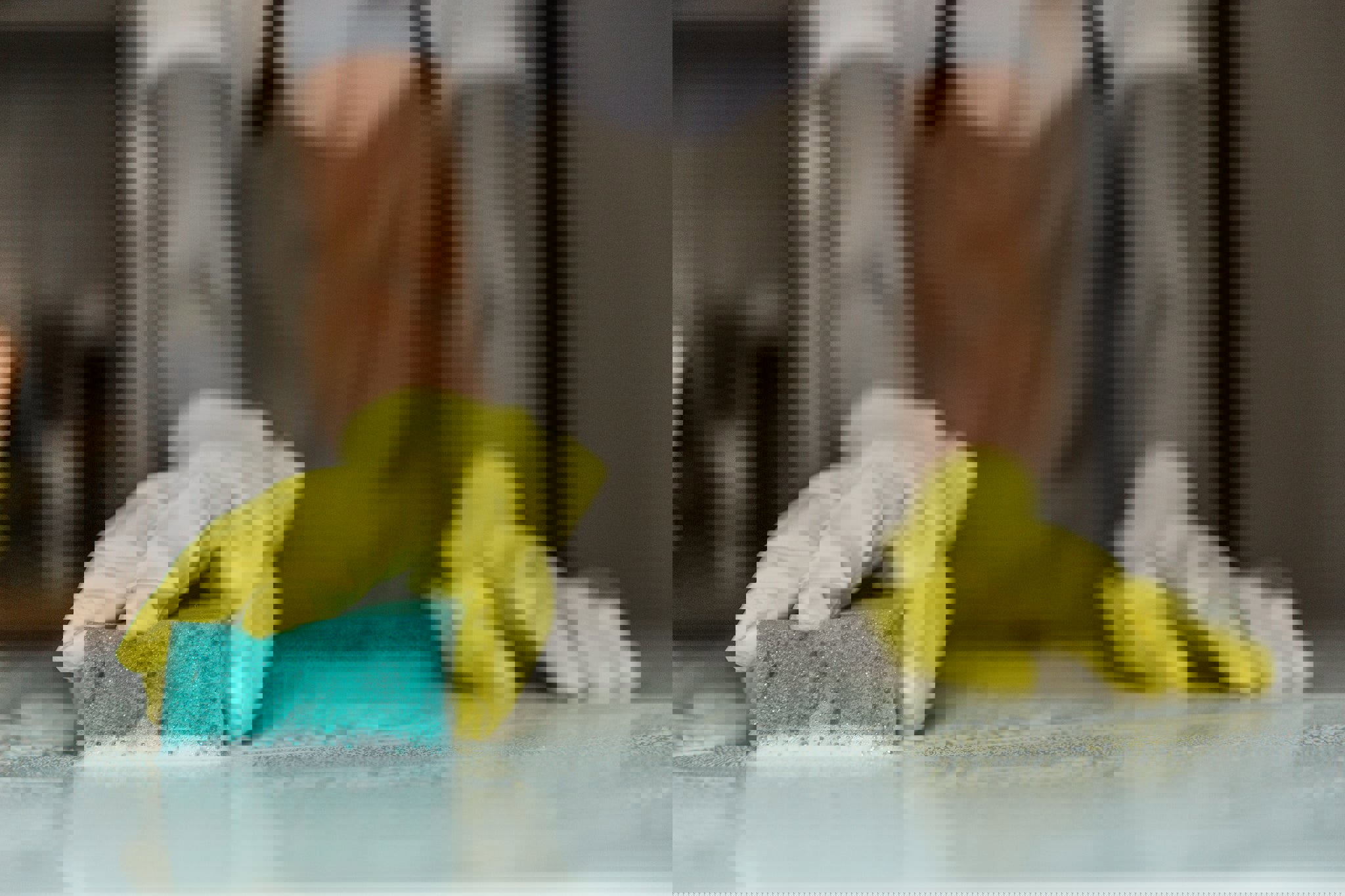 a person wearing yellow gloves is cleaning a counter with a sponge