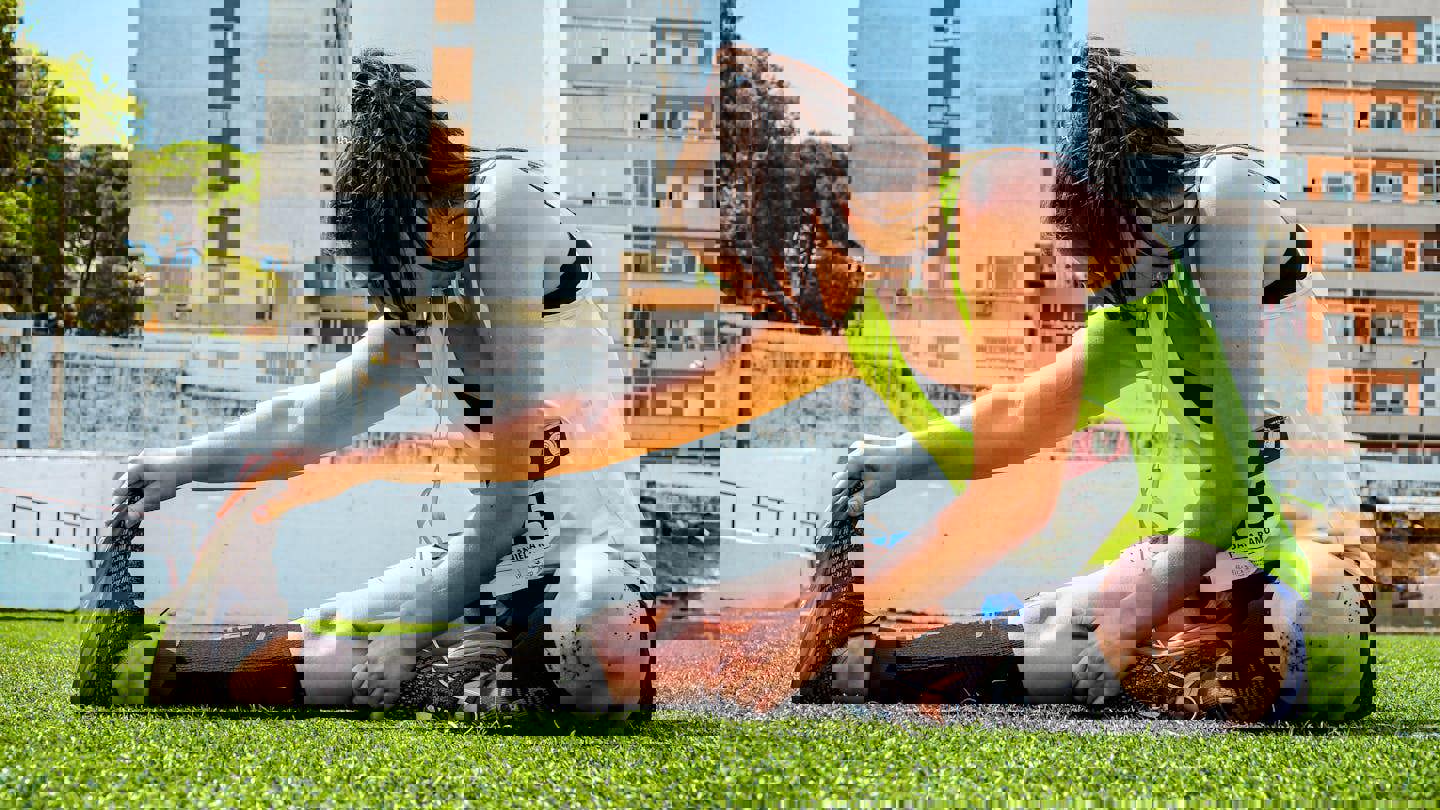 a woman wearing a yellow tank top with the number 5 on it stretches her legs