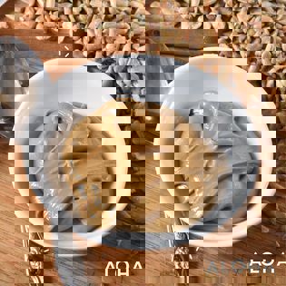 a bowl of peanut butter is sitting on a wooden table next to sunflower seeds