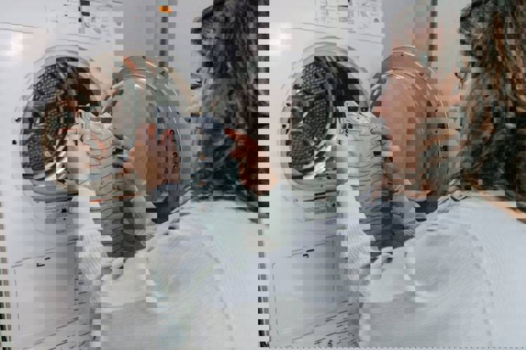 a woman is putting clothes in a washing machine