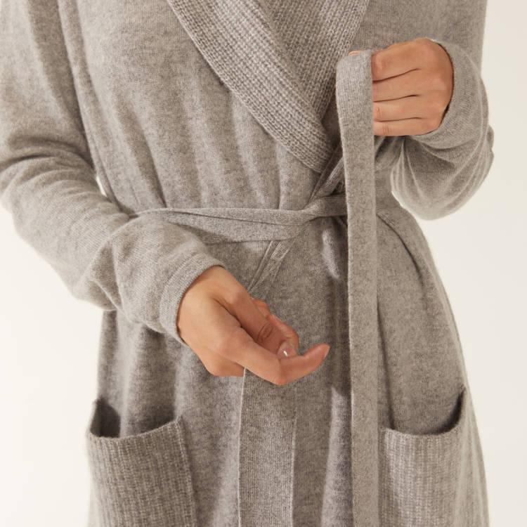 a woman is wearing a grey robe with pockets
