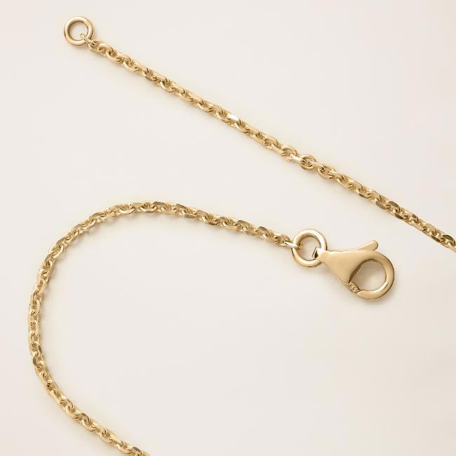 a close-up of a gold chain with a lobster clasp on a white surface