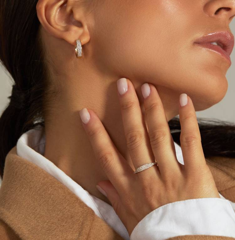 a woman is wearing a ring and earrings on her left hand