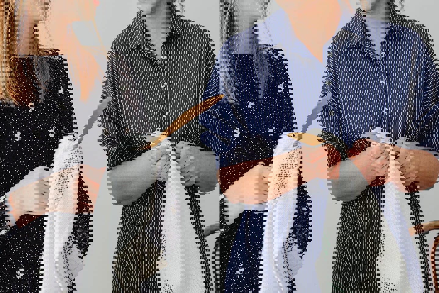 two women in striped shirts are holding clothes in their hands