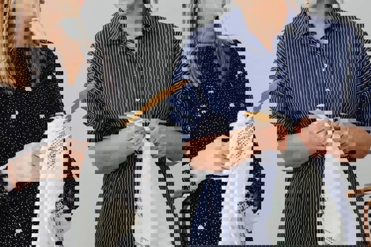 two women in striped shirts are holding clothes in their hands