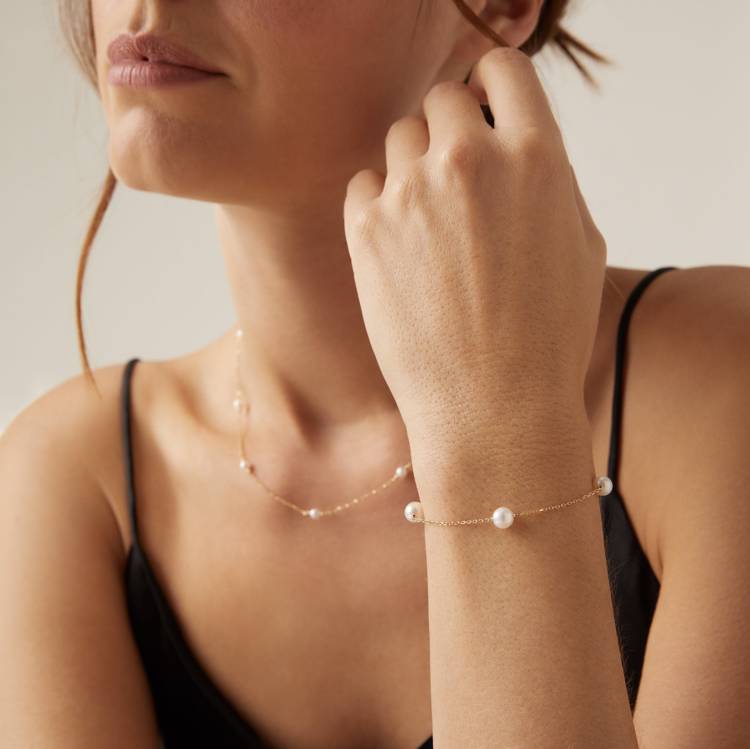 a woman is wearing a bracelet and a necklace on her wrist
