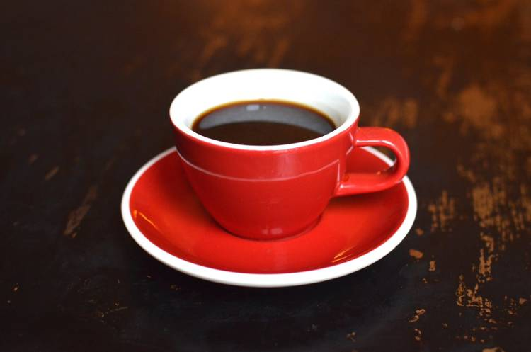 a red cup of coffee on a saucer on a table