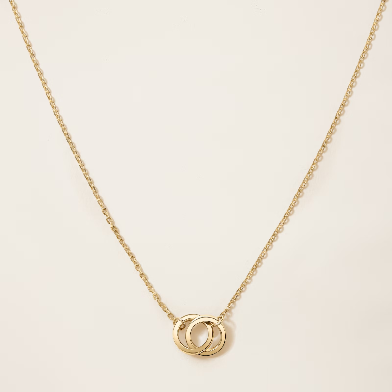 a gold necklace with two interlocking rings on a chain