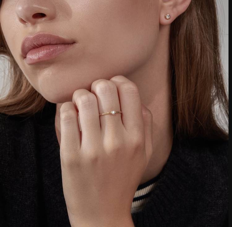 a woman is wearing a ring and earrings on her left hand