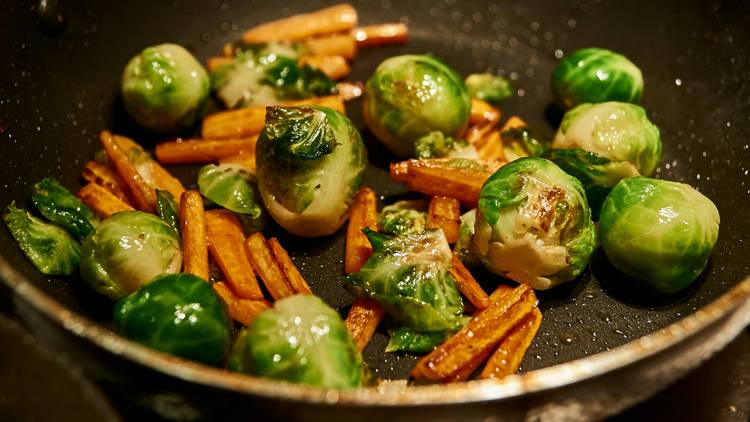 brussels sprouts and carrots are being cooked in a pan