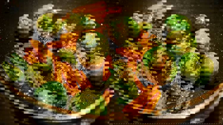 brussels sprouts and carrots are being cooked in a pan