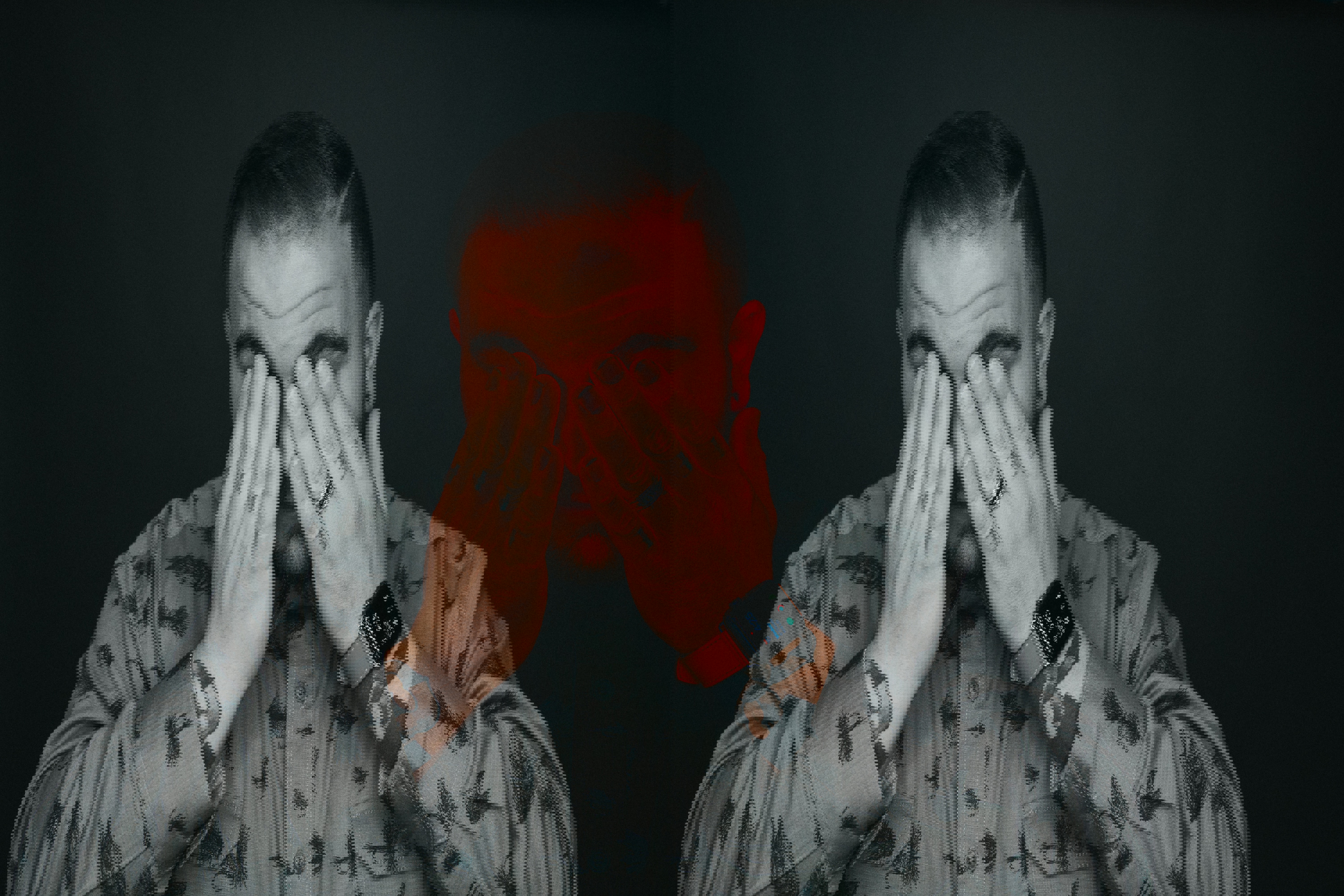 a man wearing an apple watch covering his eyes