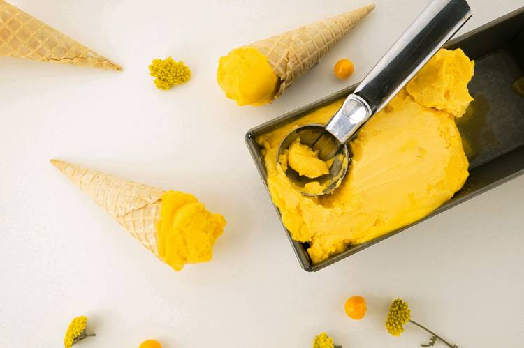 a scoop of yellow ice cream is being scooped out of a pan