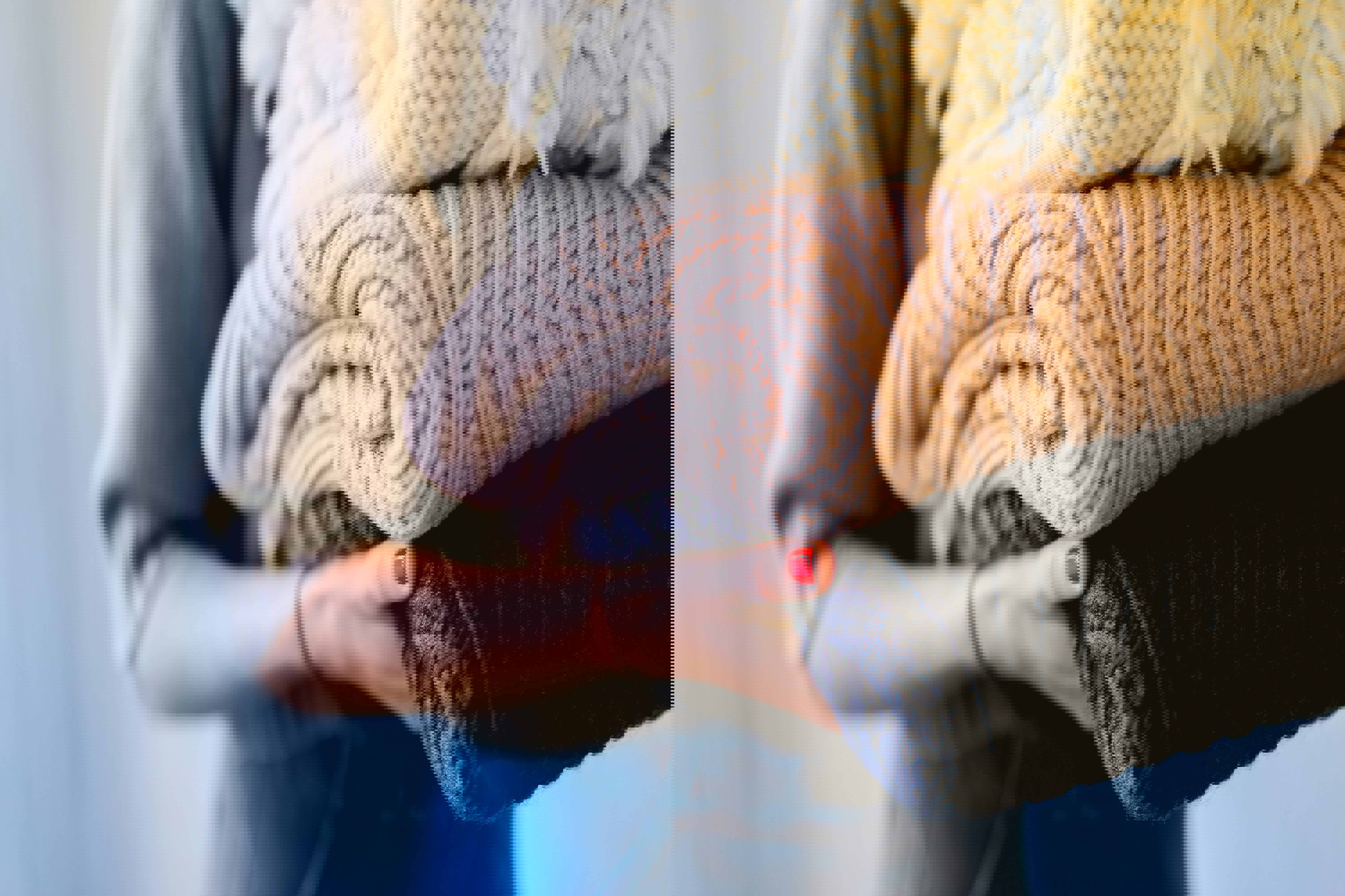 a woman with red nails is holding a pile of sweaters