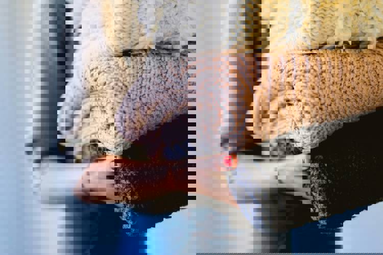 a woman with red nails is holding a pile of sweaters